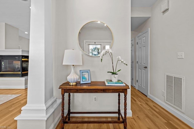 foyer with a multi sided fireplace and light hardwood / wood-style flooring