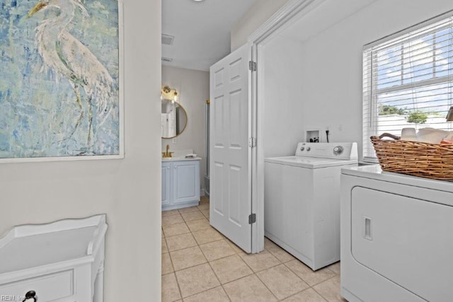 clothes washing area with washing machine and dryer, sink, and light tile patterned floors