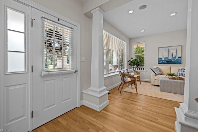 doorway to outside with light hardwood / wood-style floors and decorative columns