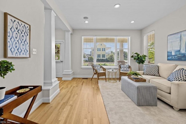 living area featuring light hardwood / wood-style floors, ornate columns, and a wealth of natural light