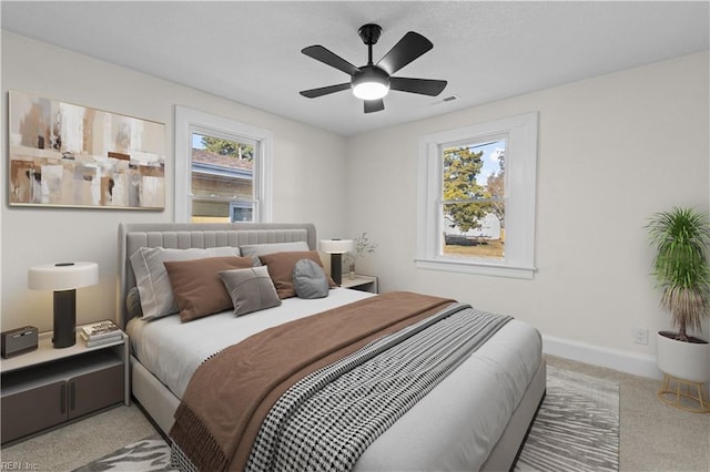 bedroom featuring ceiling fan, light carpet, and multiple windows