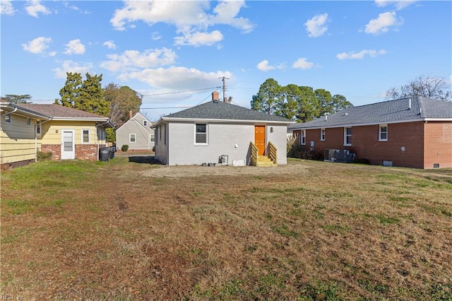 back of property with a yard and central AC