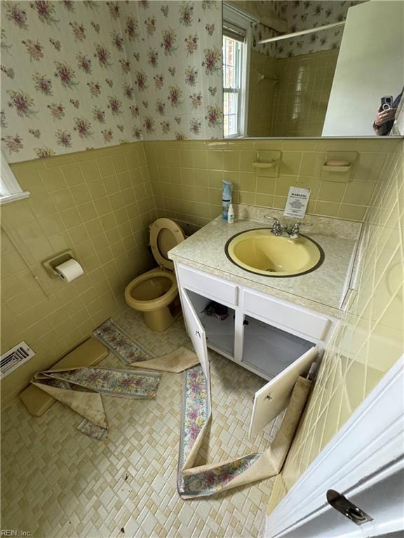 bathroom with walk in shower, vanity, tile walls, tile patterned flooring, and toilet