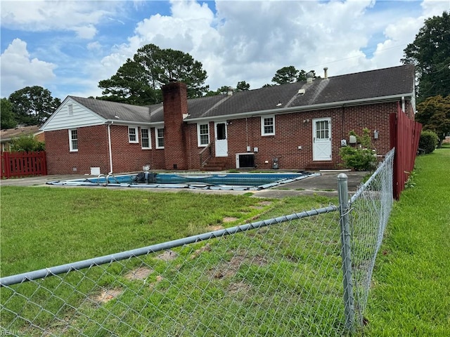 rear view of house with a covered pool and a lawn