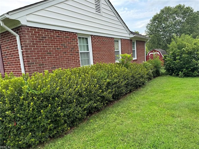 view of side of home featuring a lawn and a storage unit