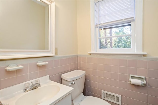 bathroom featuring vanity, tile walls, and toilet