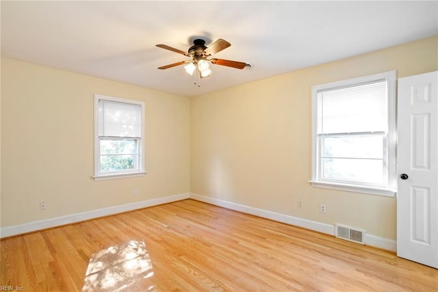 spare room with a wealth of natural light, ceiling fan, and light hardwood / wood-style floors