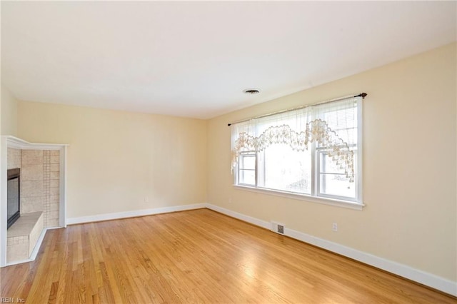 unfurnished living room featuring light wood-type flooring and a tile fireplace