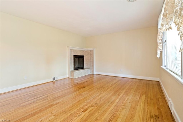 unfurnished living room featuring light hardwood / wood-style floors and a tiled fireplace