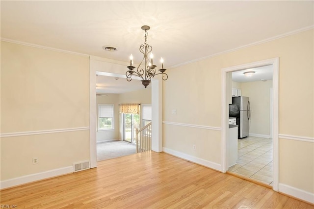 unfurnished dining area featuring hardwood / wood-style floors, ornamental molding, and an inviting chandelier