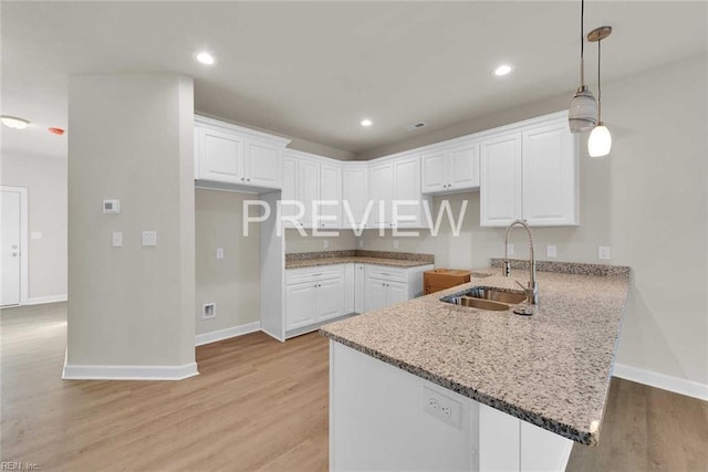 kitchen featuring white cabinets, pendant lighting, light wood-type flooring, and sink