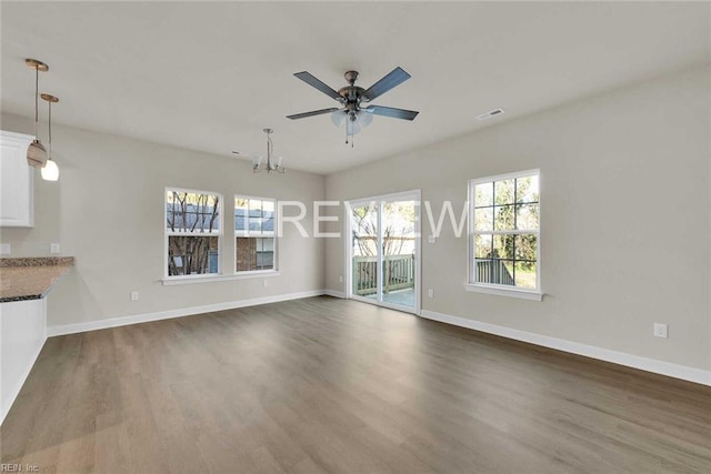 unfurnished living room with ceiling fan with notable chandelier and wood-type flooring