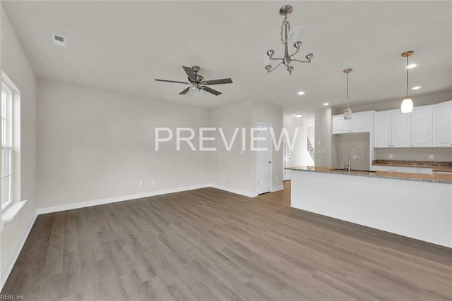 unfurnished living room with sink, ceiling fan with notable chandelier, and dark hardwood / wood-style floors