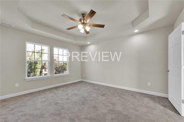 carpeted spare room featuring a raised ceiling and ceiling fan