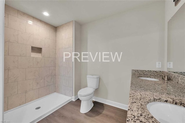 bathroom featuring hardwood / wood-style floors, vanity, a tile shower, and toilet