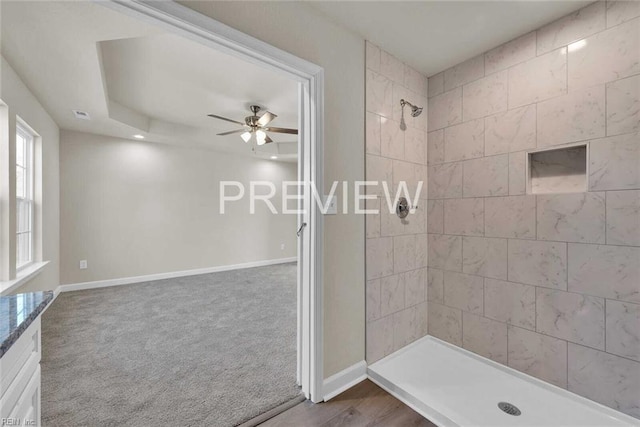 bathroom with ceiling fan, a tile shower, wood-type flooring, and vanity