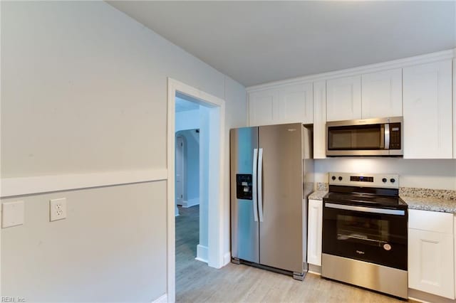 kitchen featuring light stone countertops, white cabinets, light hardwood / wood-style floors, and appliances with stainless steel finishes