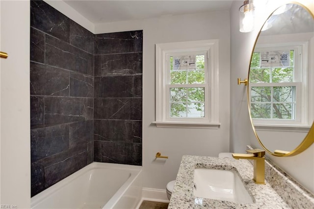 full bathroom featuring vanity, tiled shower / bath combo, and toilet