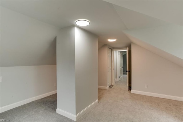 bonus room with light colored carpet and vaulted ceiling