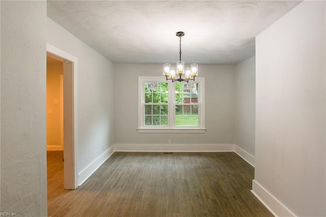 unfurnished room with dark wood-type flooring and a chandelier