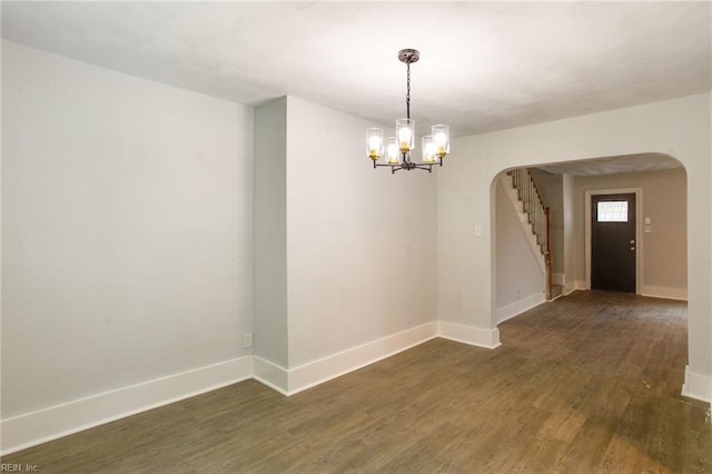 empty room with dark hardwood / wood-style floors and an inviting chandelier