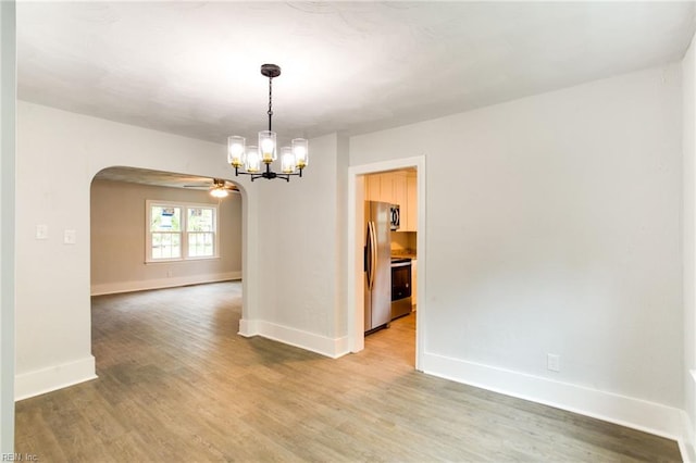 spare room featuring hardwood / wood-style flooring and ceiling fan with notable chandelier