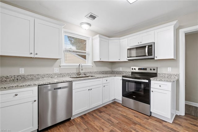 kitchen with sink, light stone counters, dark hardwood / wood-style flooring, white cabinets, and appliances with stainless steel finishes