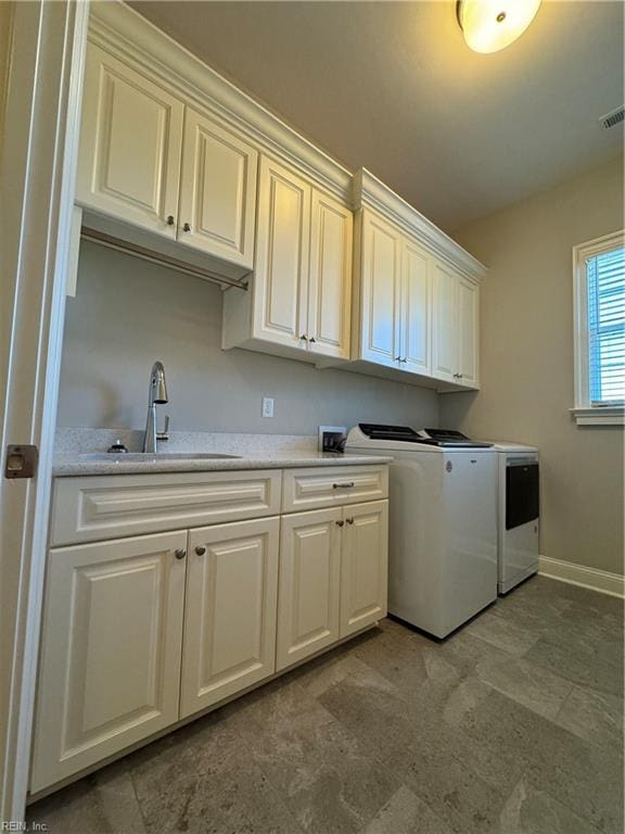 clothes washing area featuring washer and dryer, sink, and cabinets