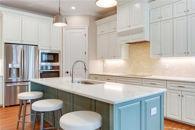 kitchen featuring white cabinetry, sink, stainless steel appliances, a kitchen island with sink, and light wood-type flooring