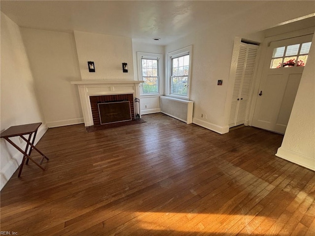 unfurnished living room with a fireplace, dark hardwood / wood-style flooring, and radiator