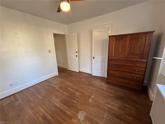 unfurnished bedroom with ceiling fan and dark wood-type flooring