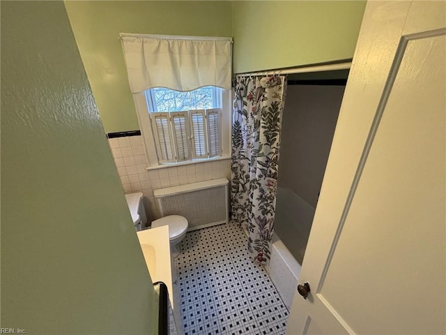 bathroom with shower / bath combo with shower curtain, radiator heating unit, tile walls, and toilet