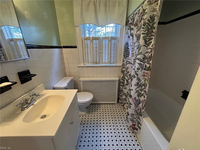 full bathroom with vanity, radiator, shower / bath combination with curtain, toilet, and tile walls