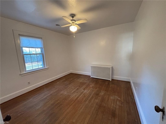 empty room featuring ceiling fan, dark hardwood / wood-style flooring, and radiator heating unit