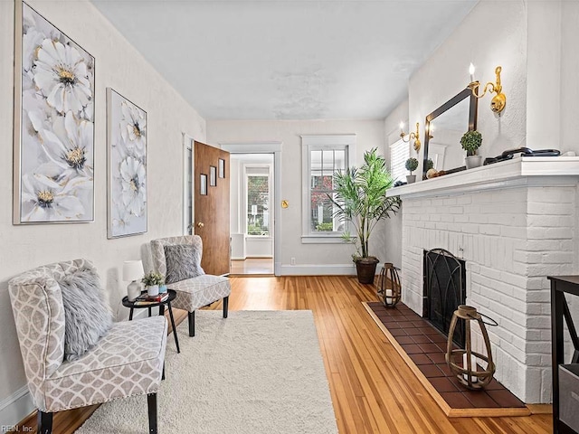 living area with wood-type flooring and a brick fireplace