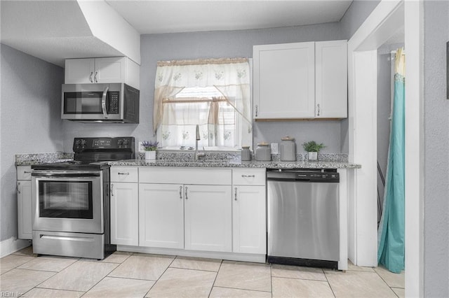 kitchen featuring white cabinets, stainless steel appliances, light stone counters, and sink