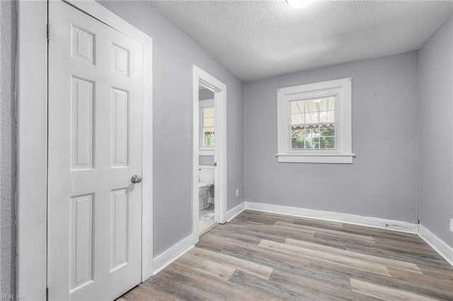 empty room with a textured ceiling and light wood-type flooring