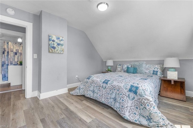 bedroom featuring light wood-type flooring and vaulted ceiling