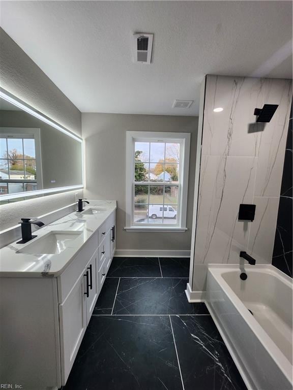 bathroom featuring plenty of natural light, vanity, a textured ceiling, and washtub / shower combination