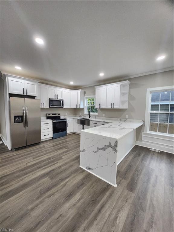 kitchen with kitchen peninsula, dark hardwood / wood-style floors, appliances with stainless steel finishes, light stone counters, and white cabinetry