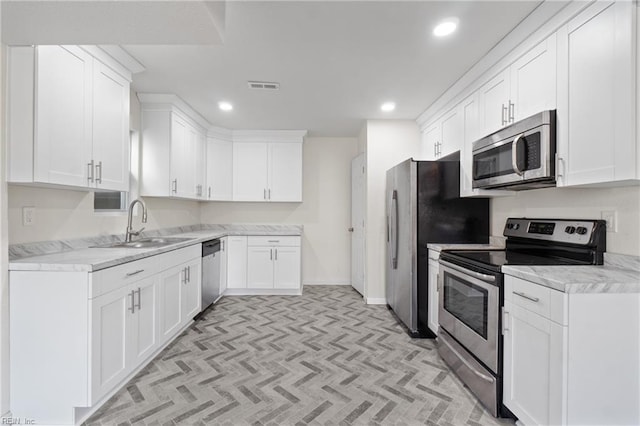 kitchen with light carpet, stainless steel appliances, white cabinetry, and sink