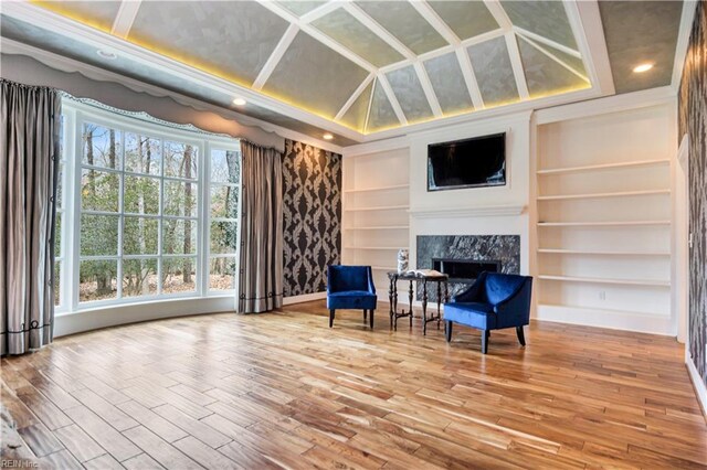 living area with a fireplace, wood-type flooring, and built in features