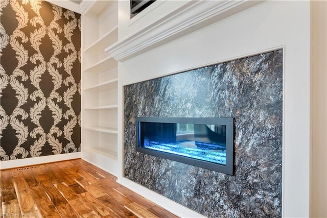 room details featuring built in shelves, wood-type flooring, and a premium fireplace