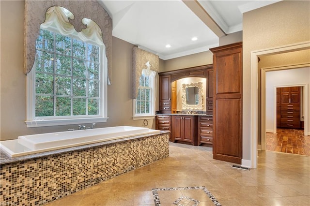 bathroom featuring wood-type flooring, vanity, tiled bath, and crown molding