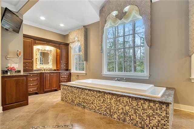 bathroom featuring vanity, a healthy amount of sunlight, and tiled bath