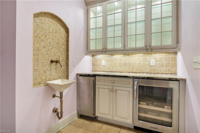 bar with decorative backsplash, light tile patterned floors, light stone counters, and beverage cooler