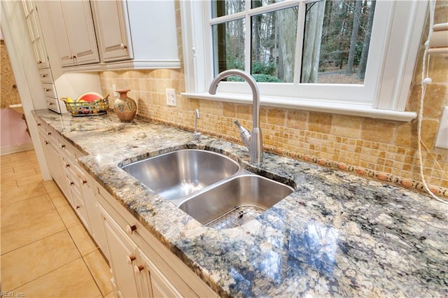 kitchen featuring decorative backsplash, light stone counters, light tile patterned floors, and sink