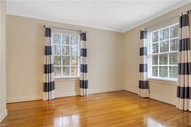 unfurnished room featuring a wealth of natural light, crown molding, and hardwood / wood-style flooring