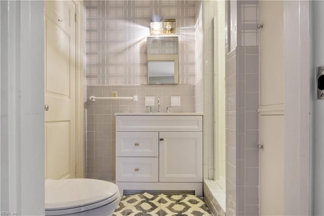 bathroom featuring vanity, toilet, and tile walls