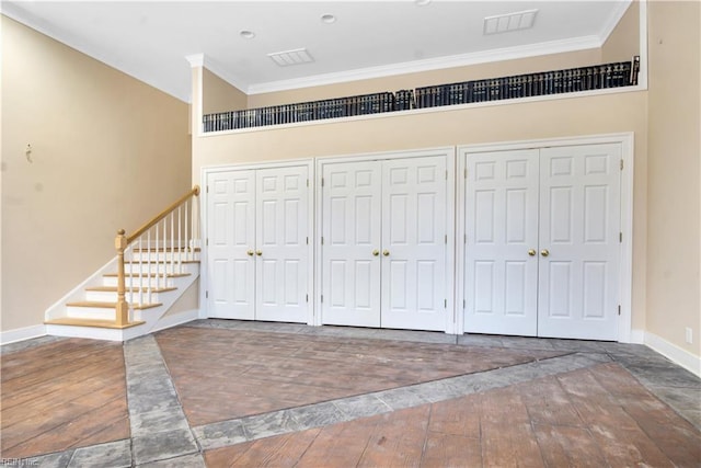 interior space with dark hardwood / wood-style floors, a towering ceiling, and crown molding